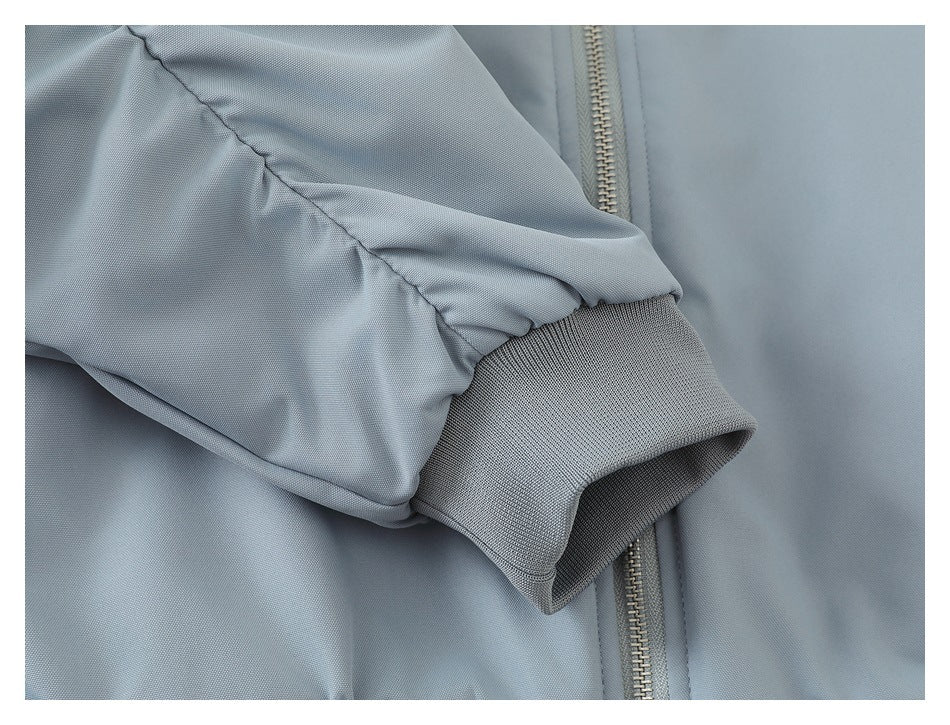 Close-up of the jacket's gathered sleeve and ribbed cuff beside the front zipper.