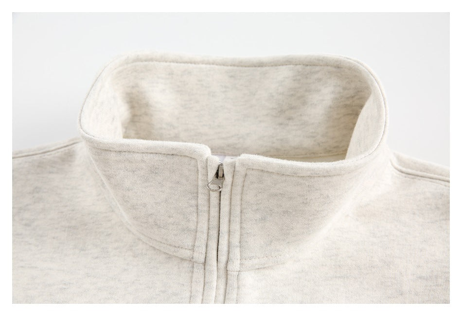 Close-up of an off-white heathered garment’s tall stand collar and centered front zipper.