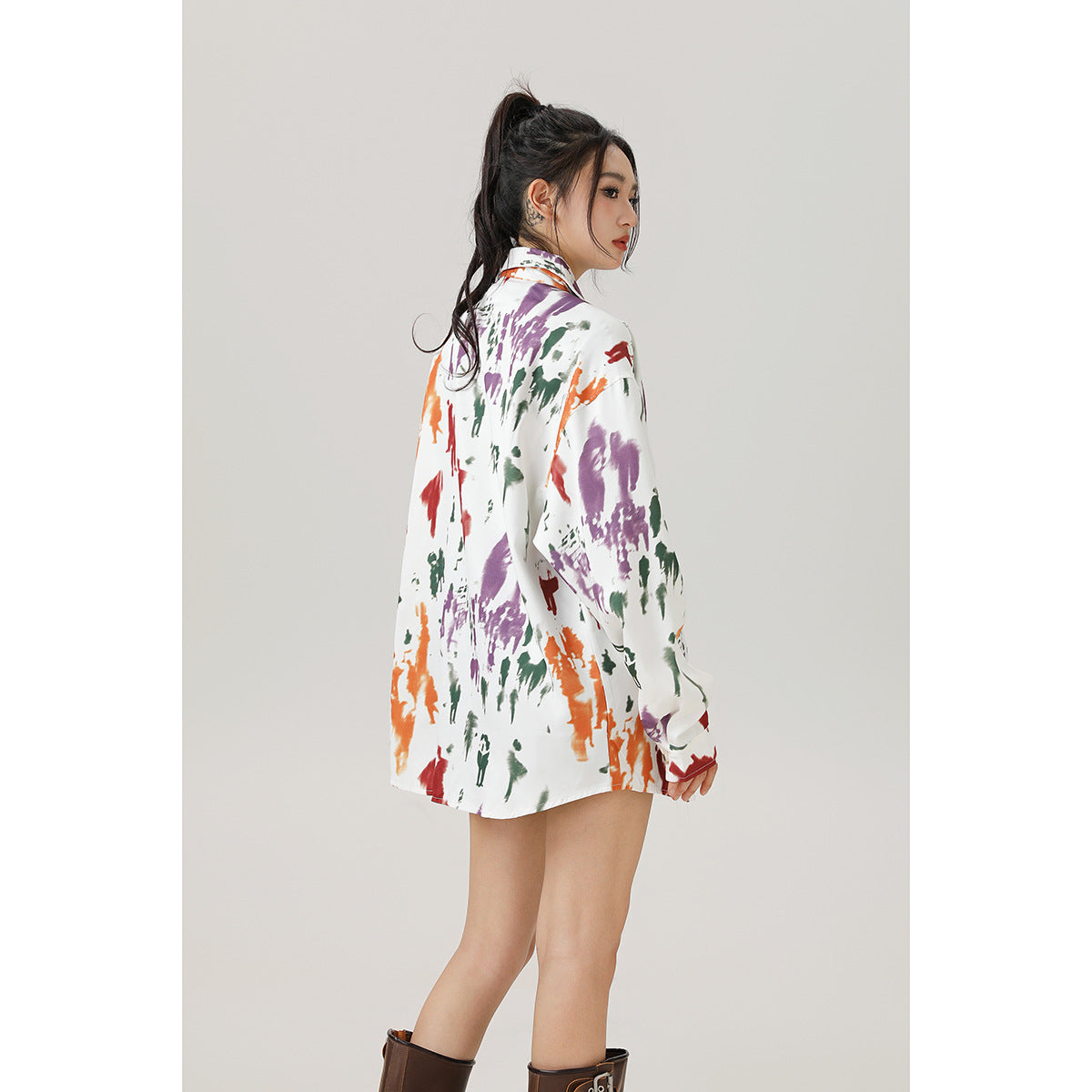 Model in a side-back view wearing an oversized white shirt with colorful abstract prints.