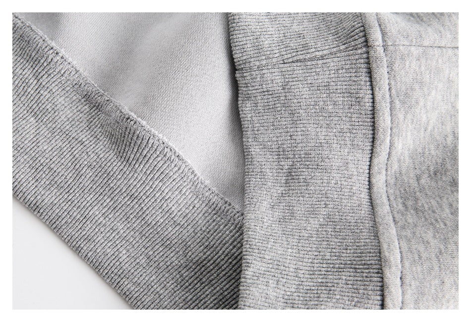 Close-up of a light gray garment showing ribbed trim and stitched seams.