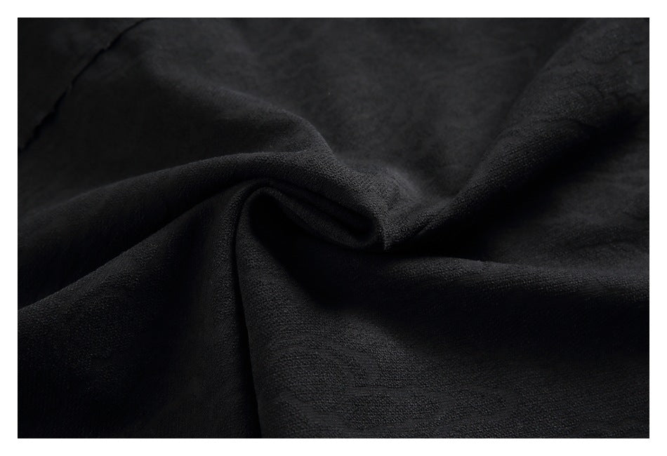 Close-up of black fabric gathered to show its subtle woven texture.