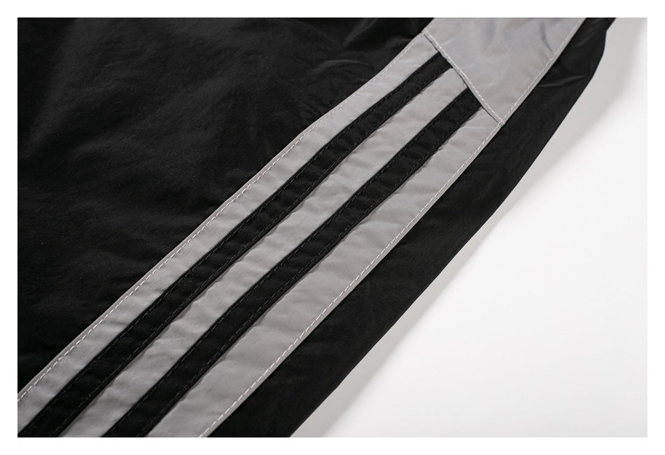 Close-up of black pants with a gray side stripe and two narrow black stripes.