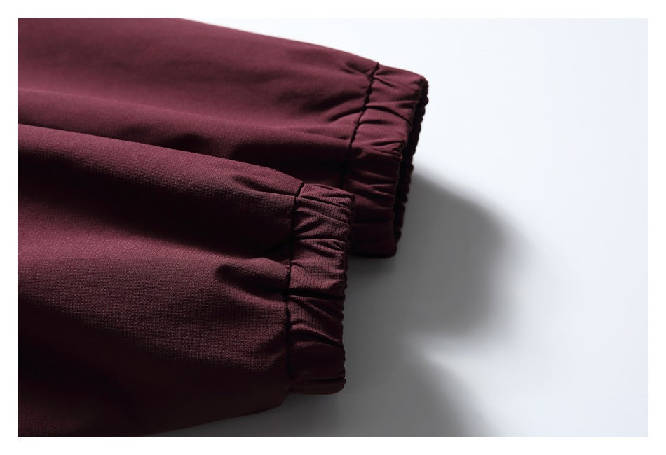 Close-up of two burgundy garment cuffs with gathered elastic edges.