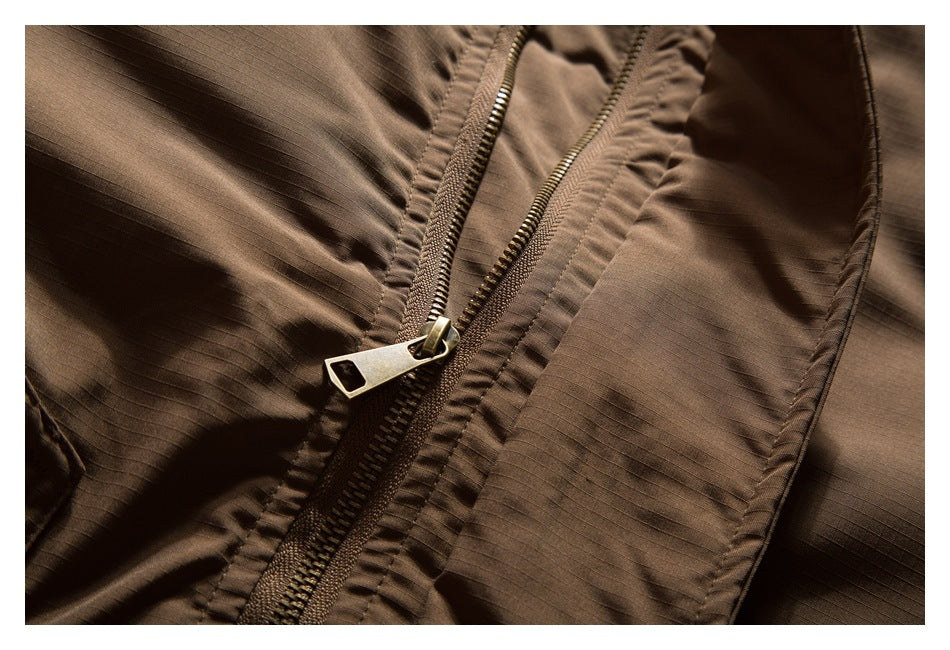 Close-up of the brown jacket's front zipper, metal pull, and surrounding stitched fabric.