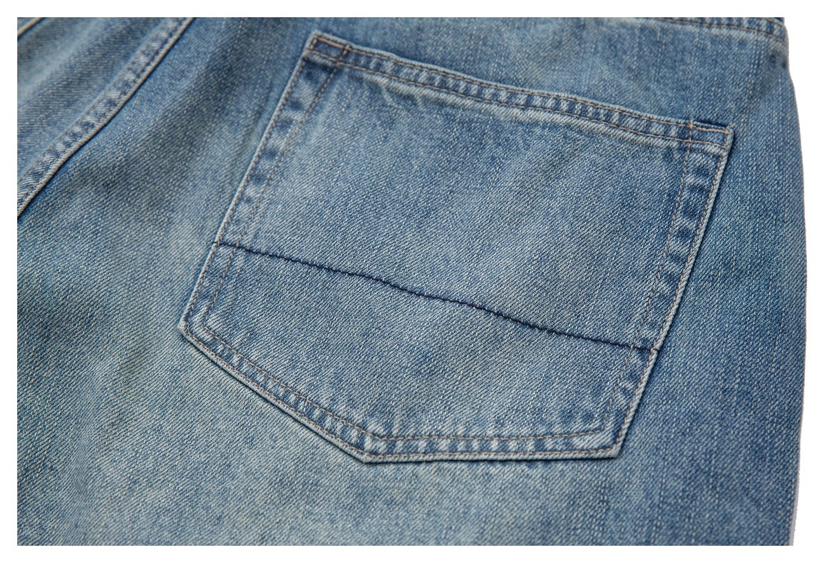 Close-up of a large stitched back pocket on faded blue denim.