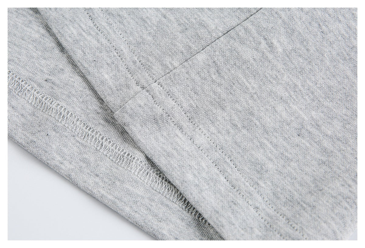 Inside view of light gray heathered knit garment showing an overlocked seam and stitching.