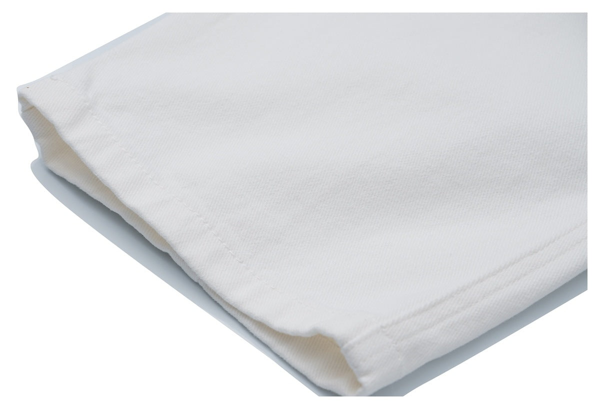 Close-up of the stitched hem and folded edge of white jeans.