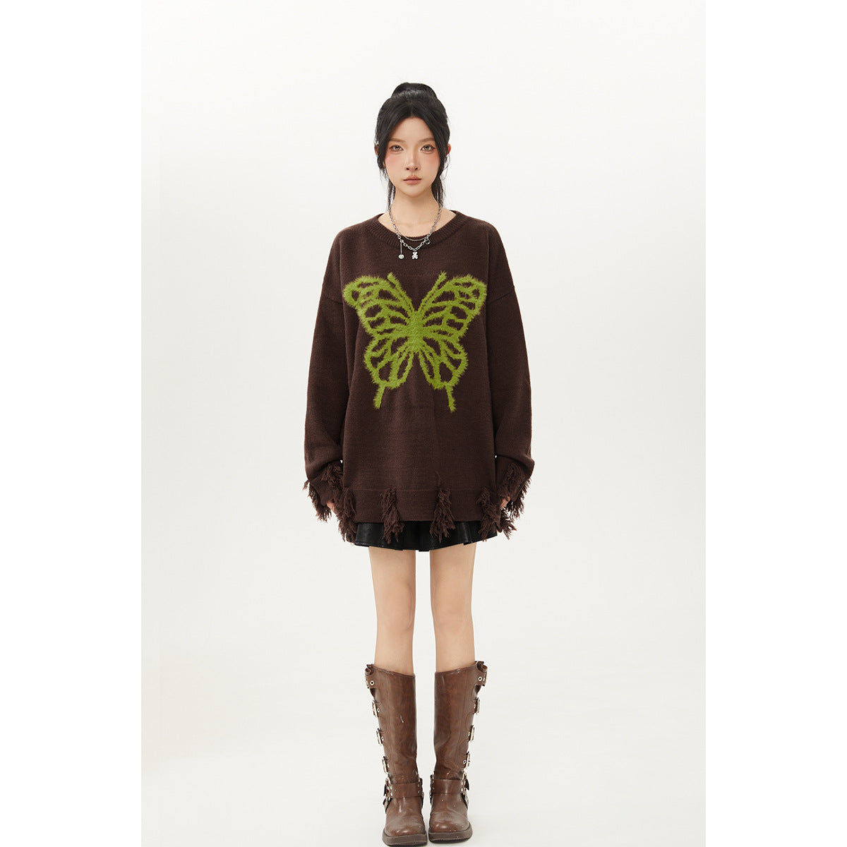 Full-length front view of a model in a dark brown oversized butterfly sweater with tasseled trim, black skirt, and brown