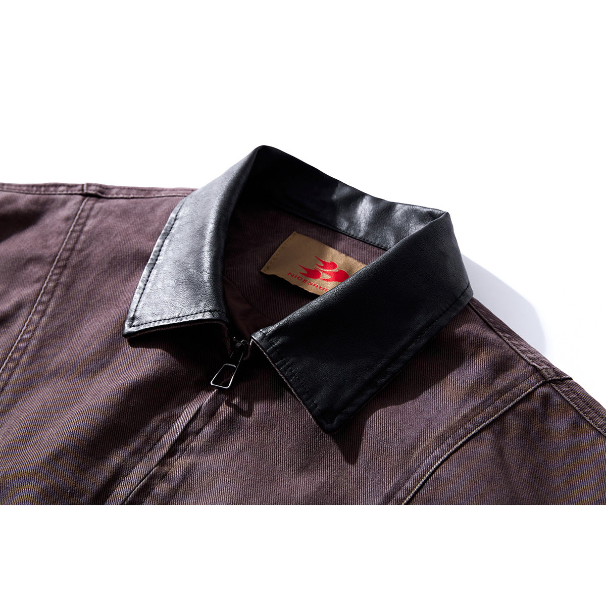 Close-up of a dark plum jacket with a black collar, front zipper, and a tan neck label.