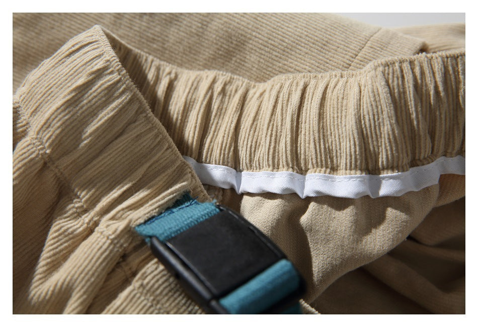 Inside view of tan corduroy pants with a gathered waistband and teal-and-black webbing hardware.