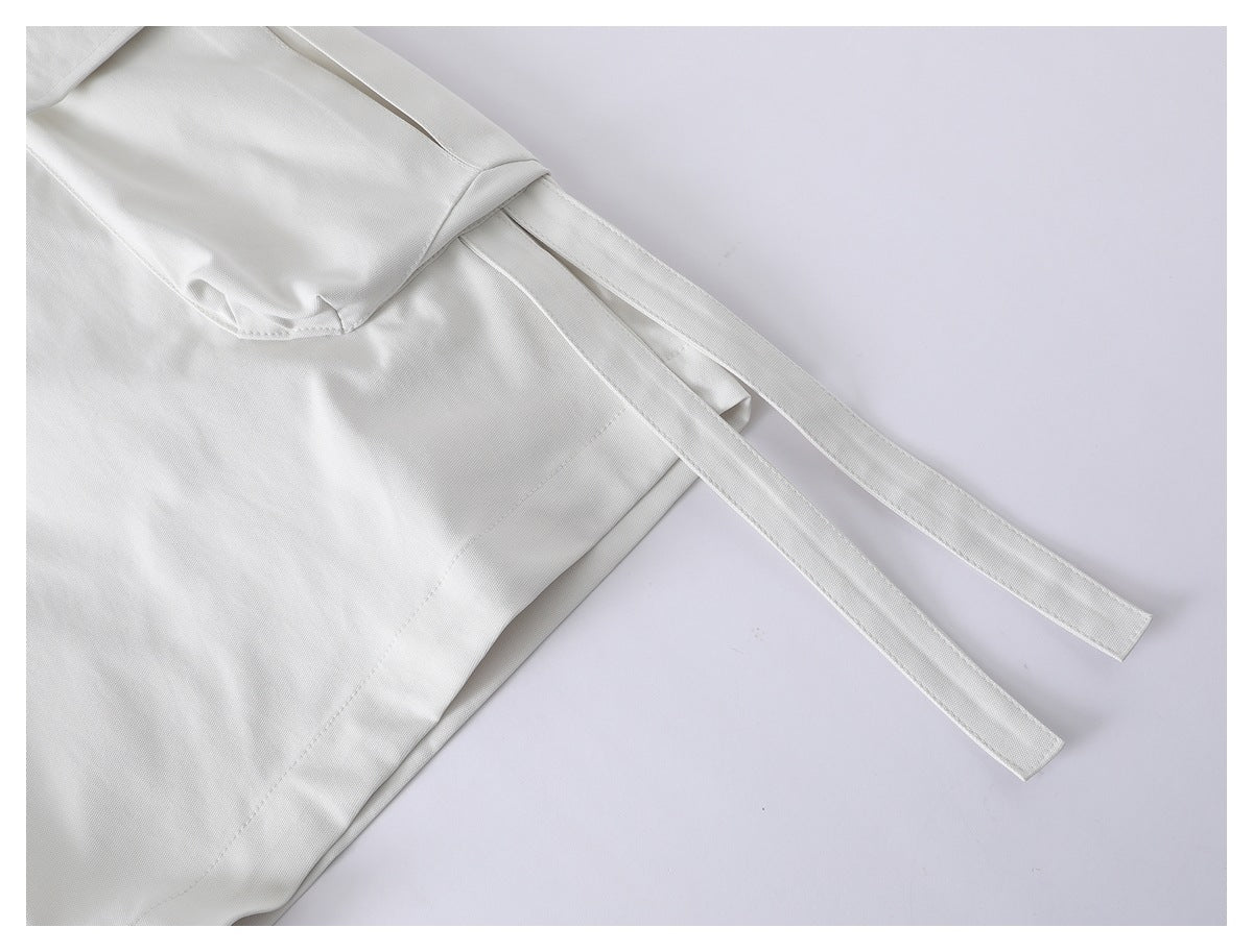 Close-up of the white shorts' long side ties beside a cargo pocket flap.