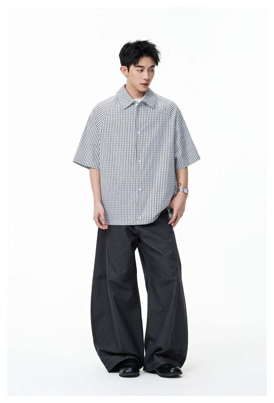 Full-length view of a model wearing a gray-and-white gingham short-sleeve shirt and dark wide-leg trousers.