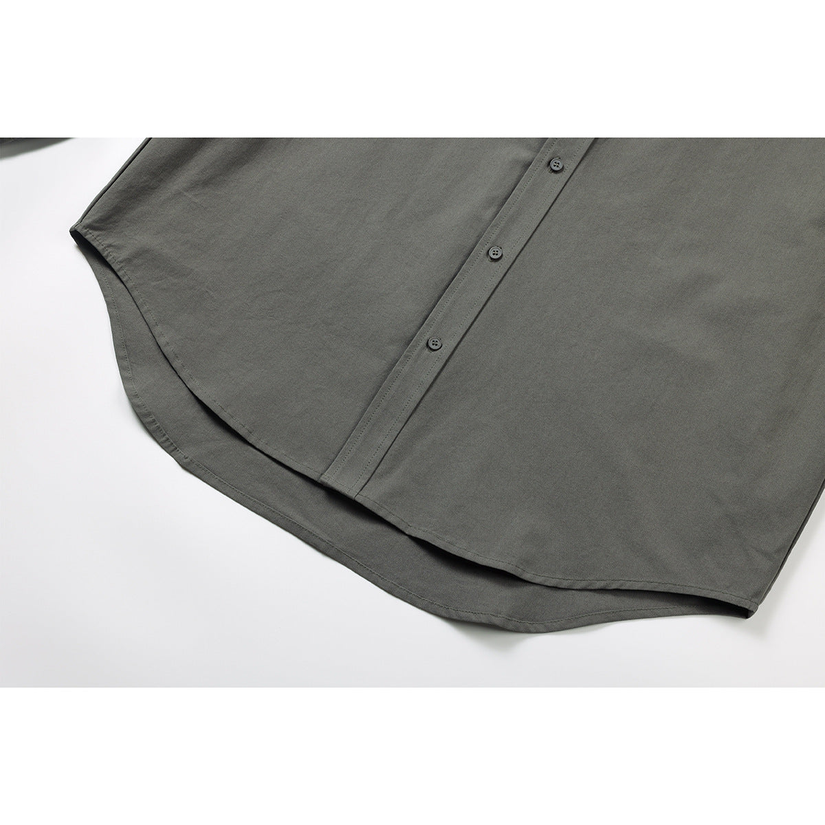 Close-up of the gray-green shirt's button placket and curved hem.