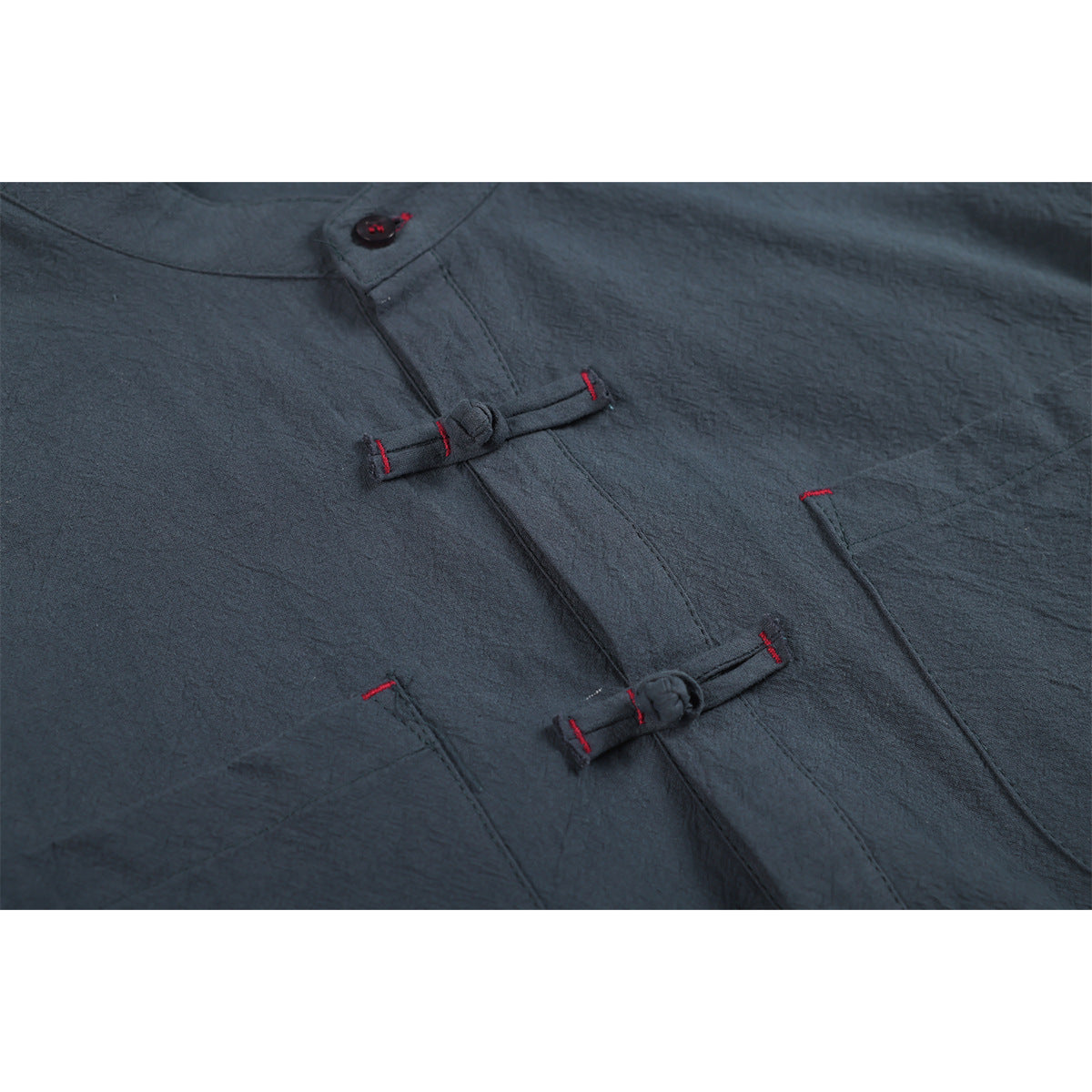 Close-up of a dark slate shirt front with frog closures, pockets, and red stitching.