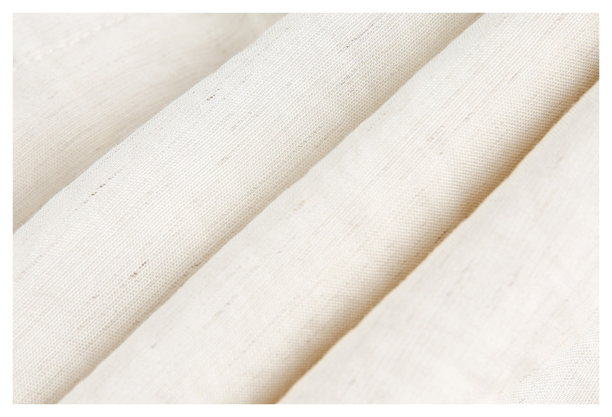 Macro view of the cream fabric's woven texture and natural flecks.