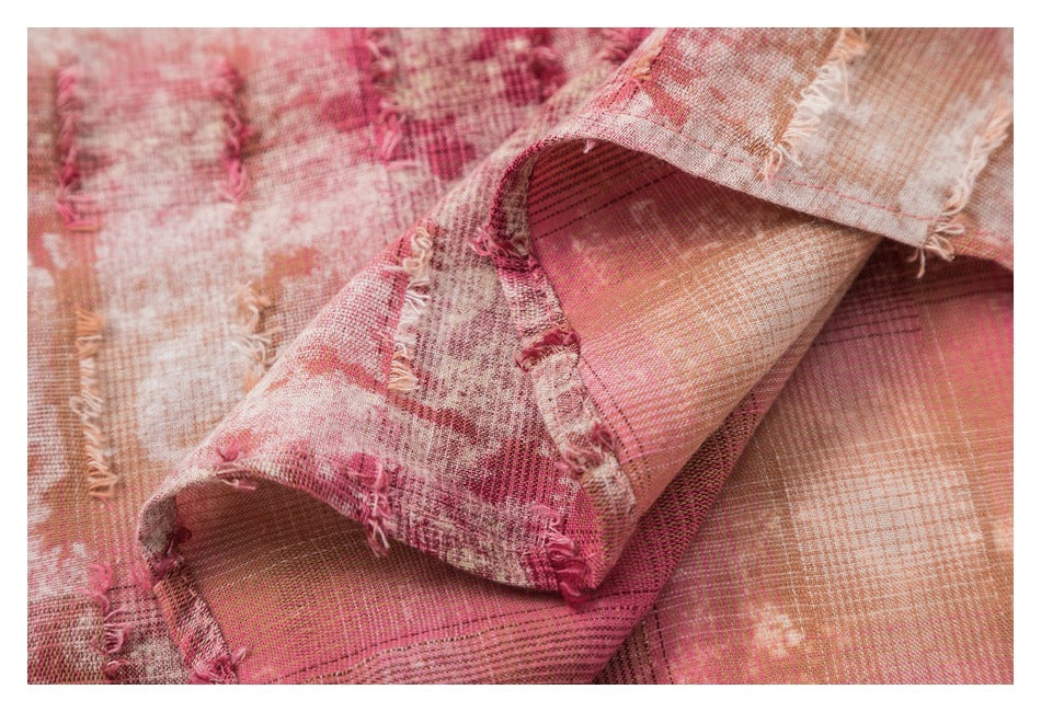 Close-up of folded dusty rose and cream checked fabric showing frayed edges and stitching.