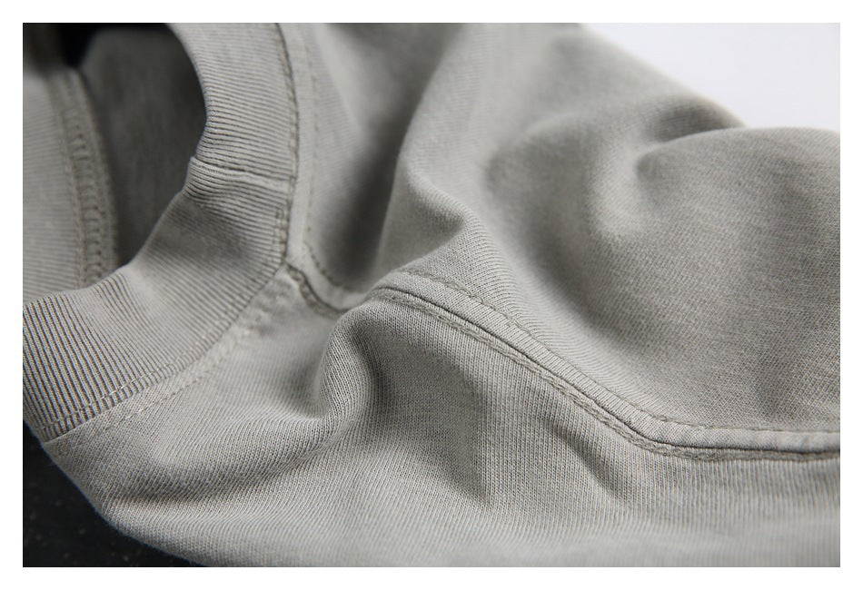 Close-up of a light gray garment showing a ribbed neckline and curved shoulder seam.