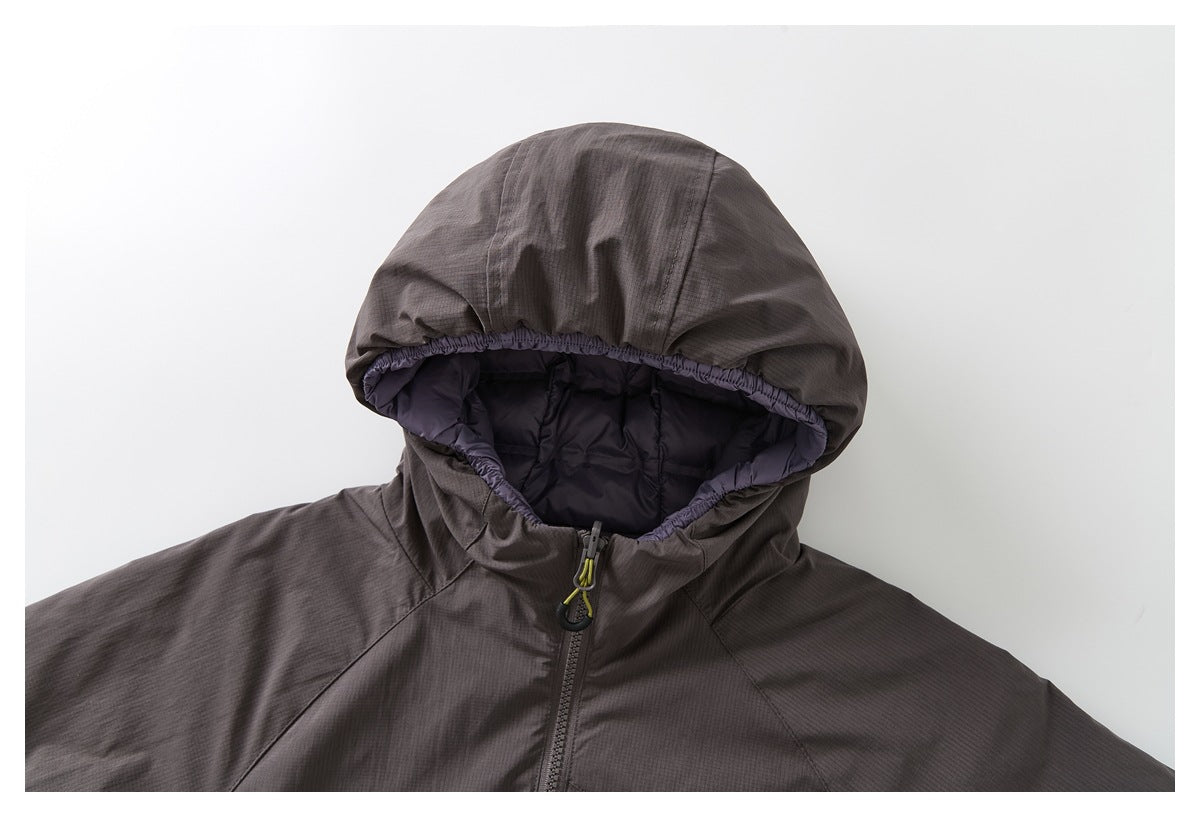 Close-up of a dark charcoal hooded jacket showing its padded lining, gathered hood edge and front zipper.