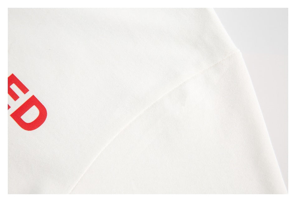 Close-up of white fabric with a diagonal seam and a cropped red printed graphic.
