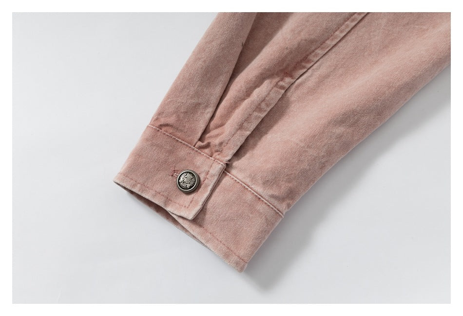 Close-up of a cuff with a decorative metal button on dusty rose fabric.