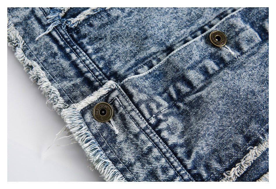 Close-up of blue acid-wash denim with antique-tone buttons and heavily frayed edges.