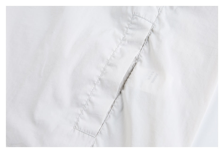 Close-up of a white jacket seam and stitched fabric panel.