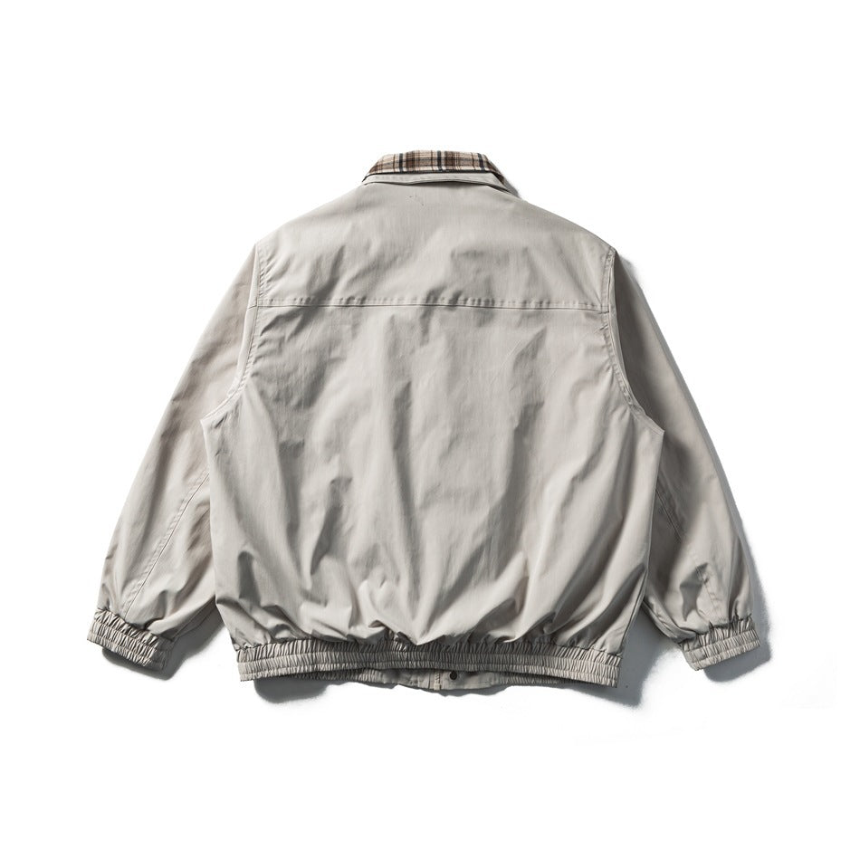 Back view of a light gray jacket with elasticated cuffs and waistband and a plaid collar.