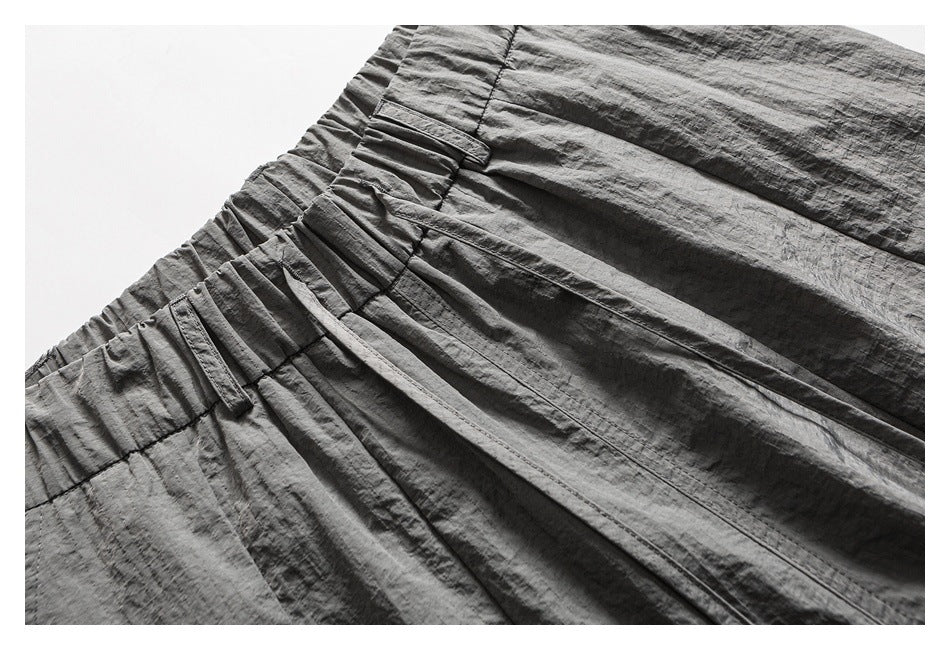 Close-up of gray cargo pants showing the gathered waistband, belt loops, stitching, and pocket details.