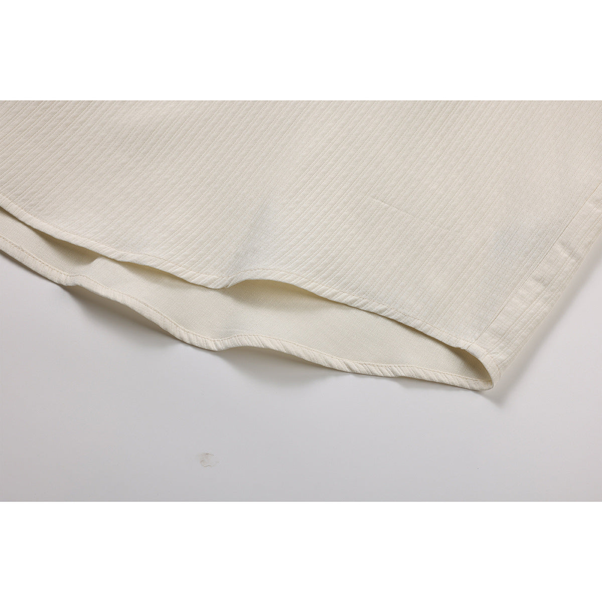 Close-up of the ivory shirt's ribbed fabric and curved double-layer hem.