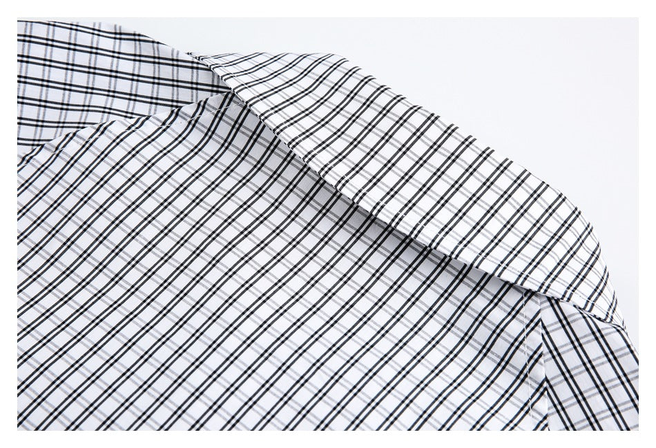 Close-up of a white shirt collar and shoulder with a black and gray windowpane plaid pattern.