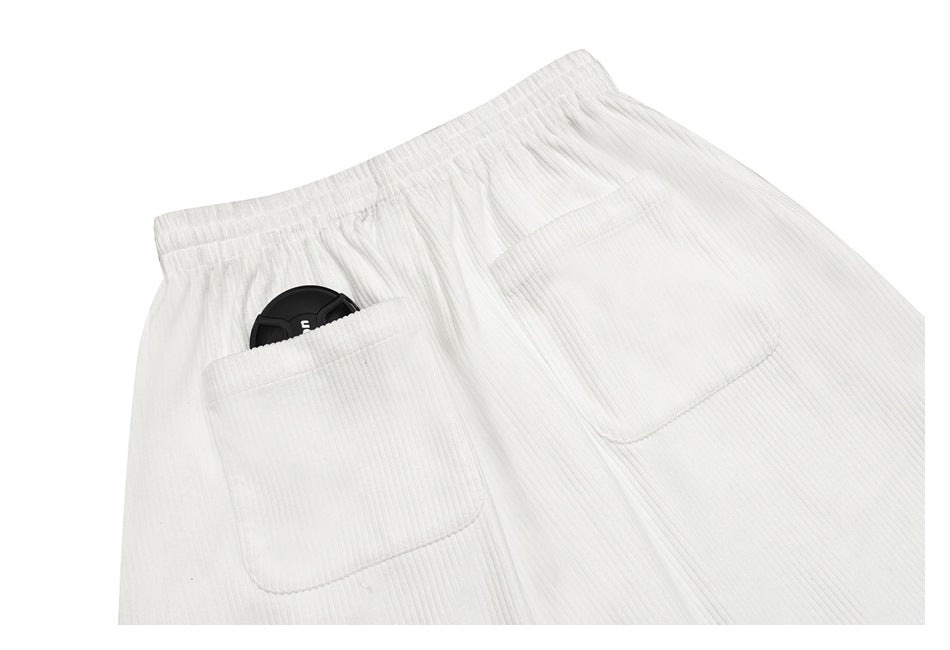 Close-up of white ribbed shorts showing the elastic waistband and two front pockets.