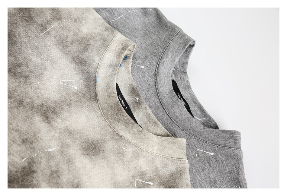 Close-up of overlapping beige and gray T-shirt necklines, showing ribbed collars and black sewn-in brand labels.