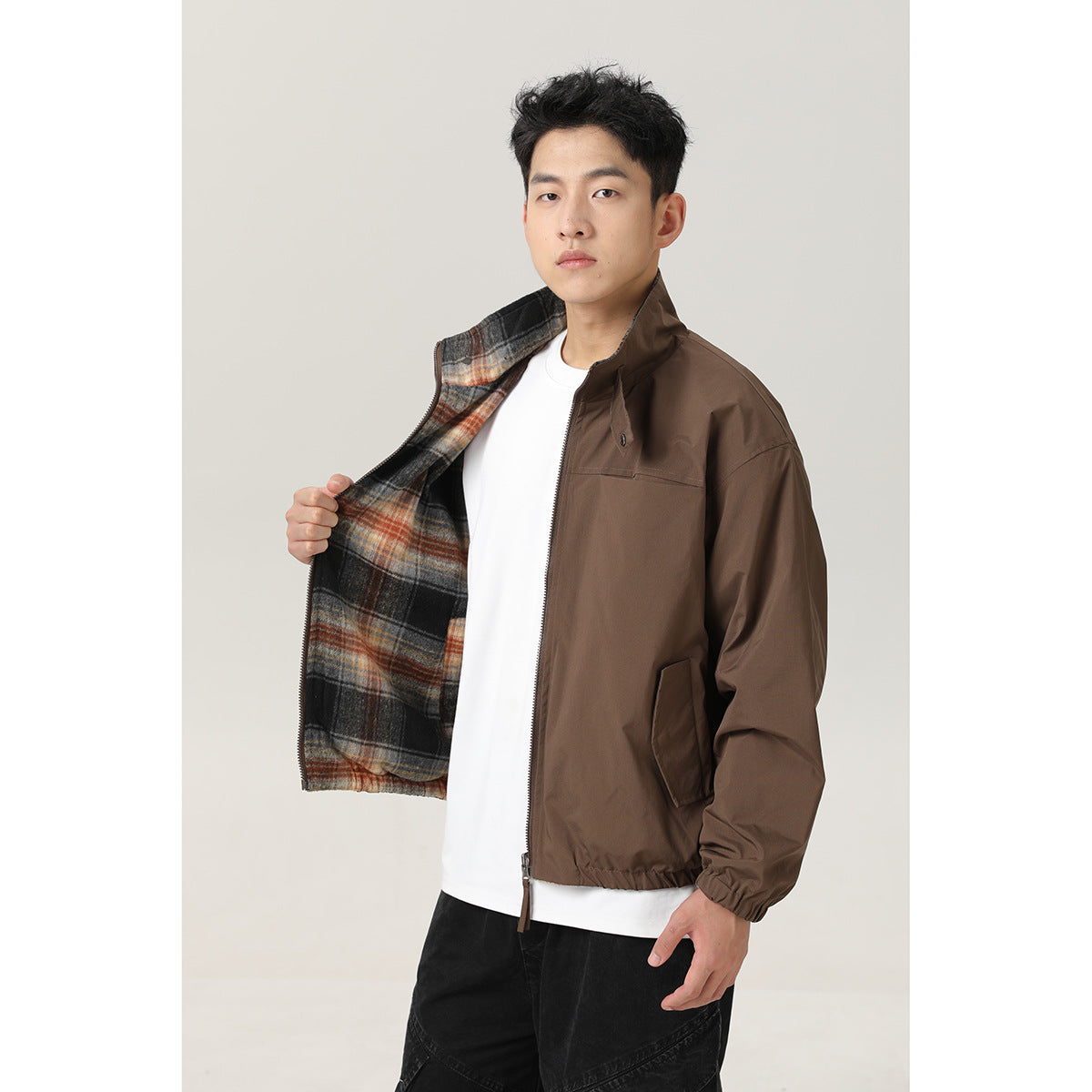 Model wears a brown zip jacket open to show its black, gray, and rust plaid lining.