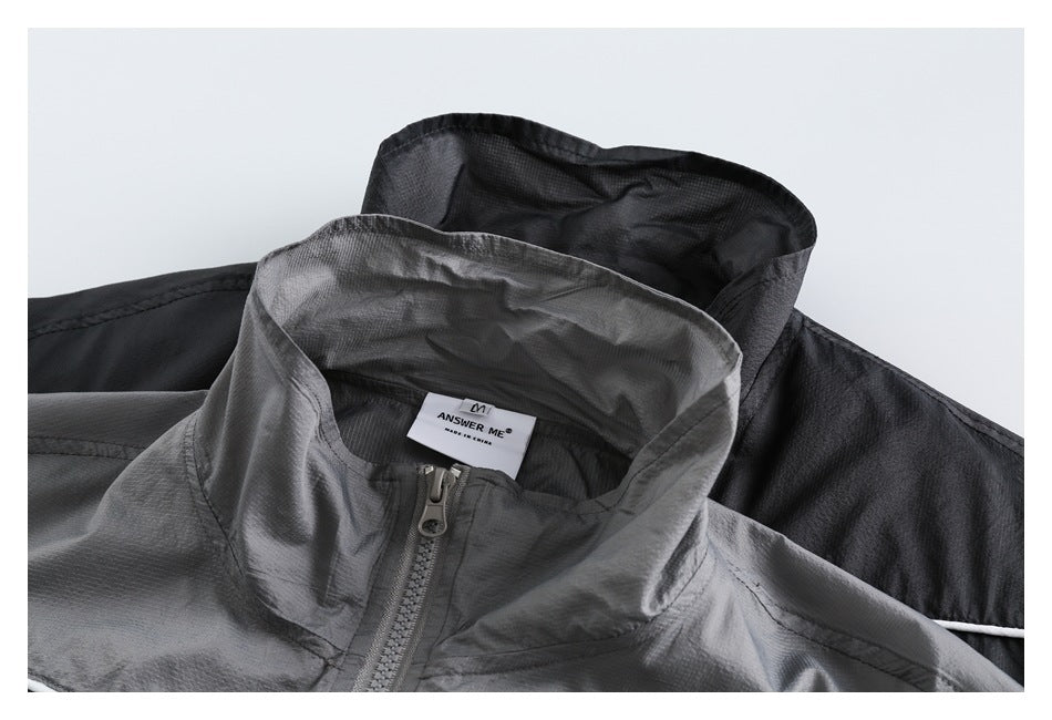 Close-up of the gray jacket’s stand collar, zipper, and neck label, with part of a black jacket behind it.