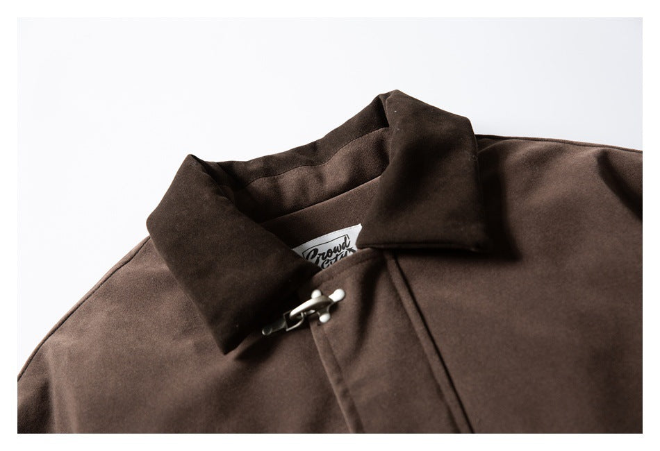 Close-up of a dark brown jacket collar, silver clasp, and partially visible neck label.