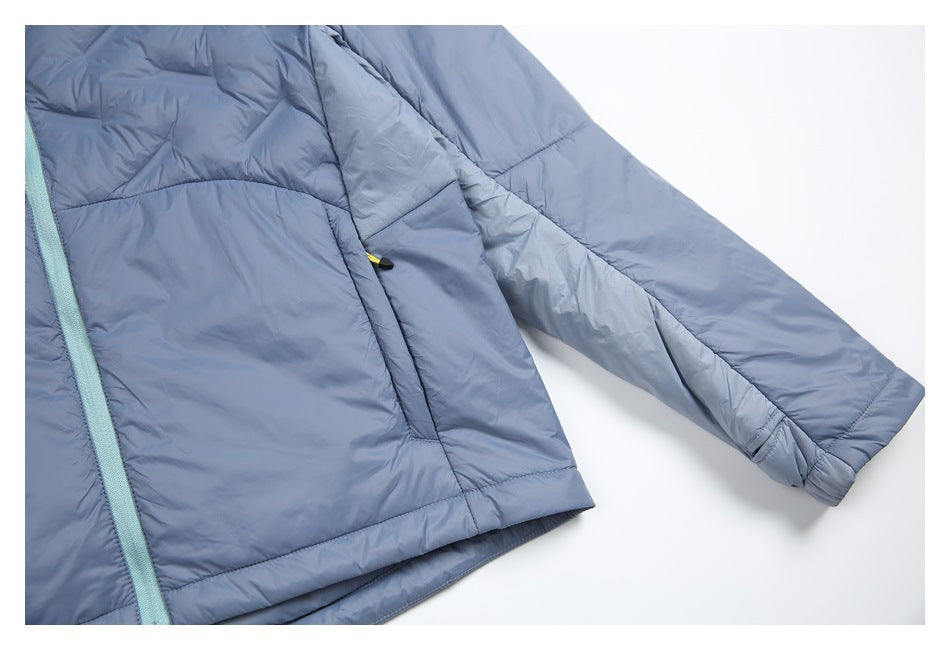 Close view of a slate-blue padded jacket body and sleeve with stitched panels and a pale aqua zipper.