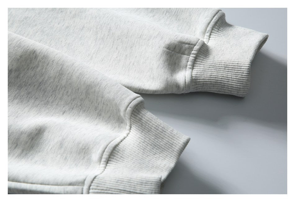 Two ribbed sleeve cuffs on a light gray heathered garment, shown laid flat.