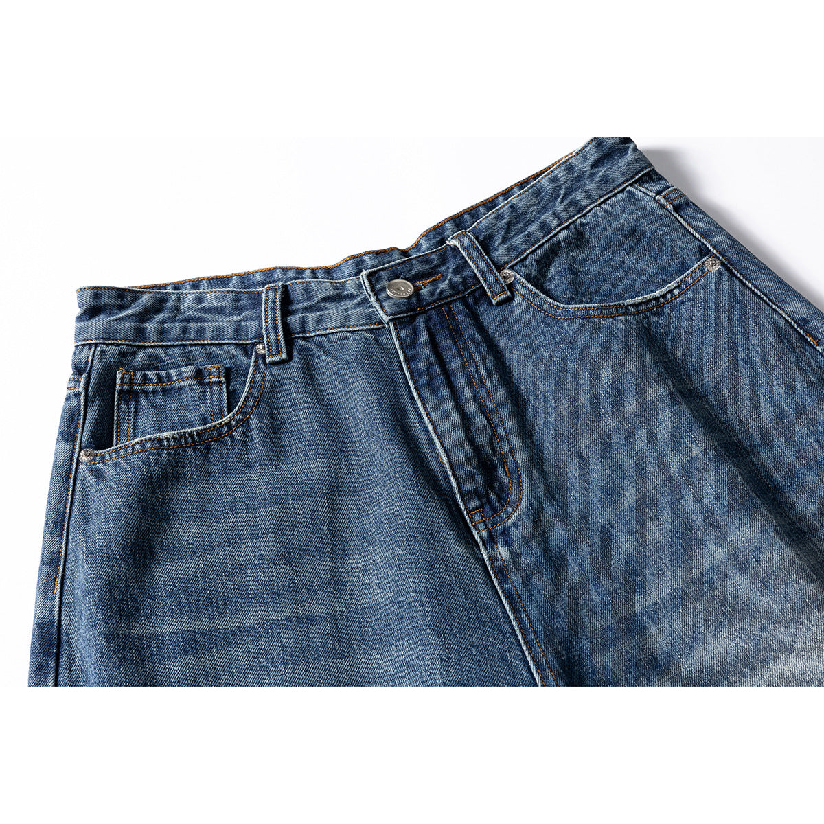 Close-up of blue washed jeans showing the waistband, button, belt loops, and front pockets.