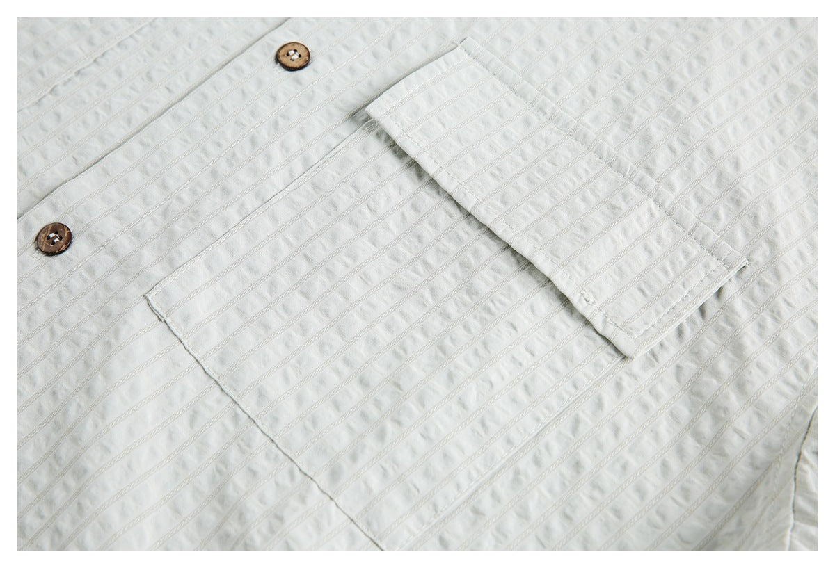 Close-up of a white shirt's rectangular chest pocket, brown buttons, and raised vertical stripe texture.