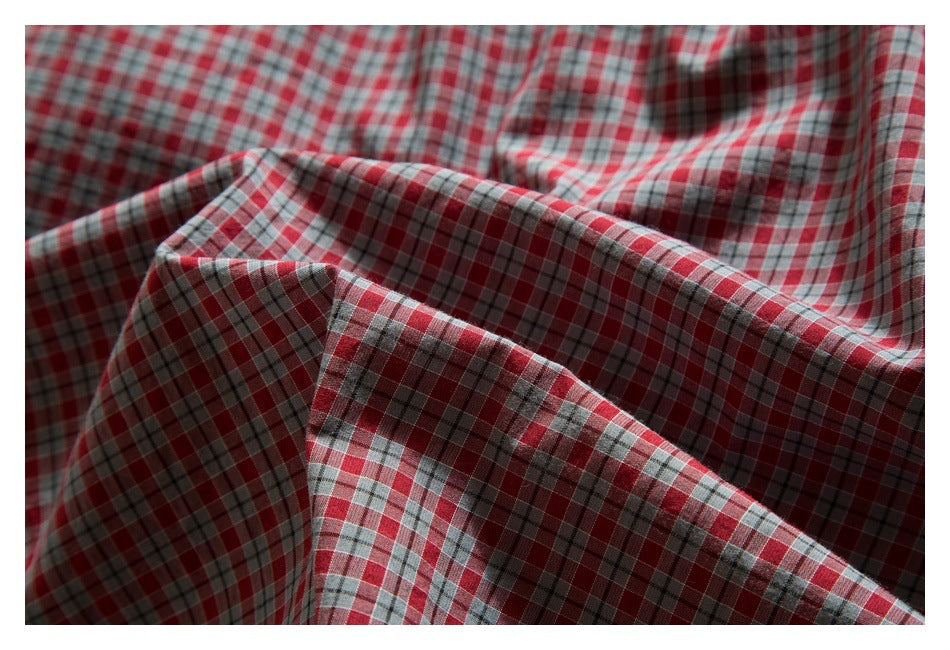 Close-up of draped red, gray, and white plaid fabric with fine intersecting checks.
