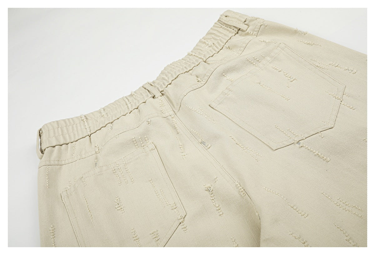 Close-up of beige trousers showing the back waistband, belt loops, and two patch pockets with raised stitching.