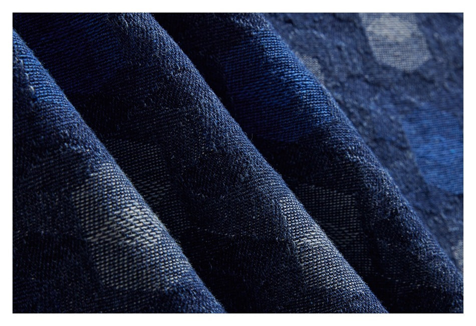 Macro view of folded dark blue shirt fabric showing a subtle geometric pattern.