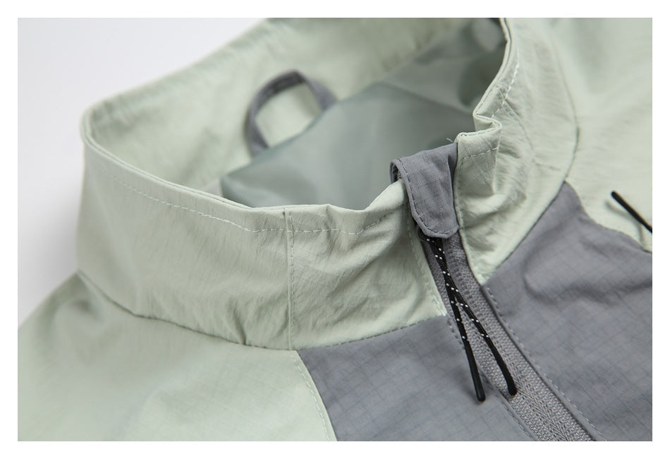 Close-up of the jacket's pale sage stand collar, gray front panel, and zipper with a fabric flap.