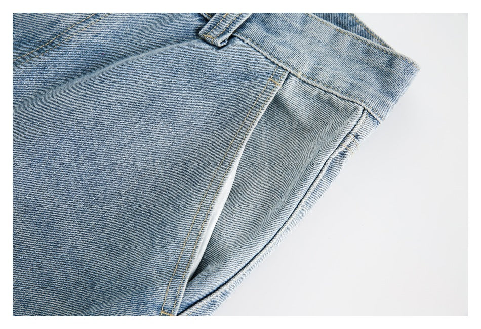 Close-up of pale blue denim jeans showing a curved pocket opening and contrast stitching.