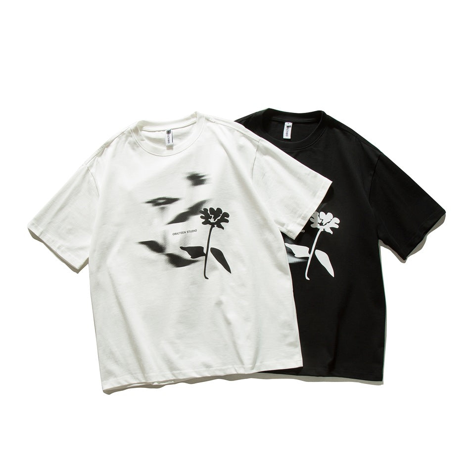Off-white and black crew-neck T-shirts with short sleeves and contrasting flower graphics, shown from the front.