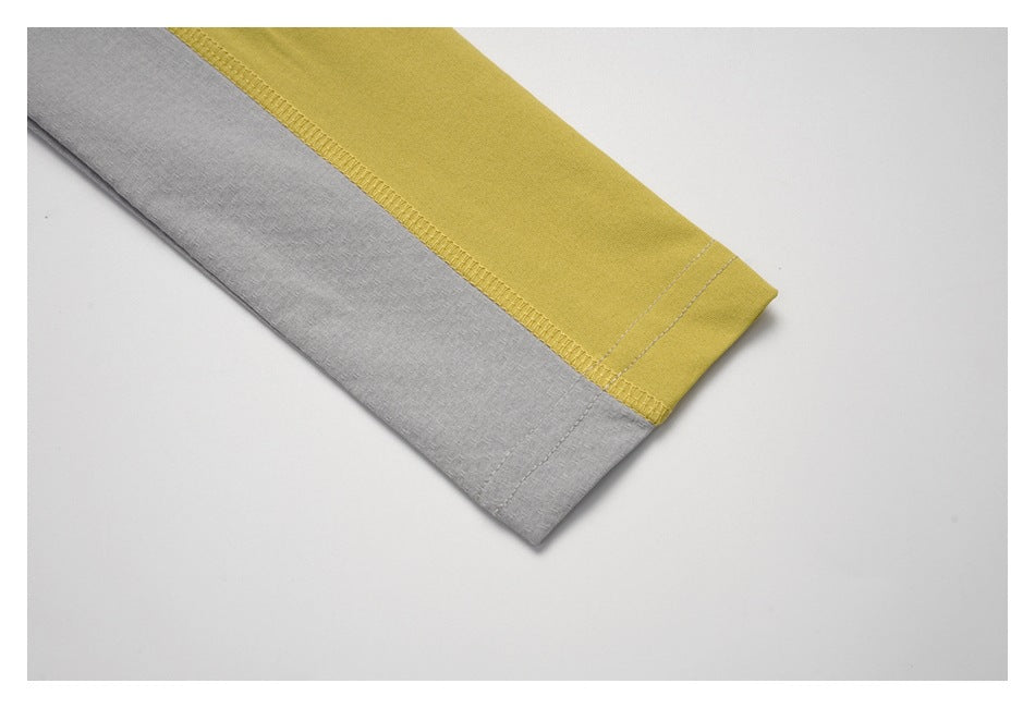 Close-up of a gray sleeve with a wide mustard-yellow color-block panel and stitched cuff.