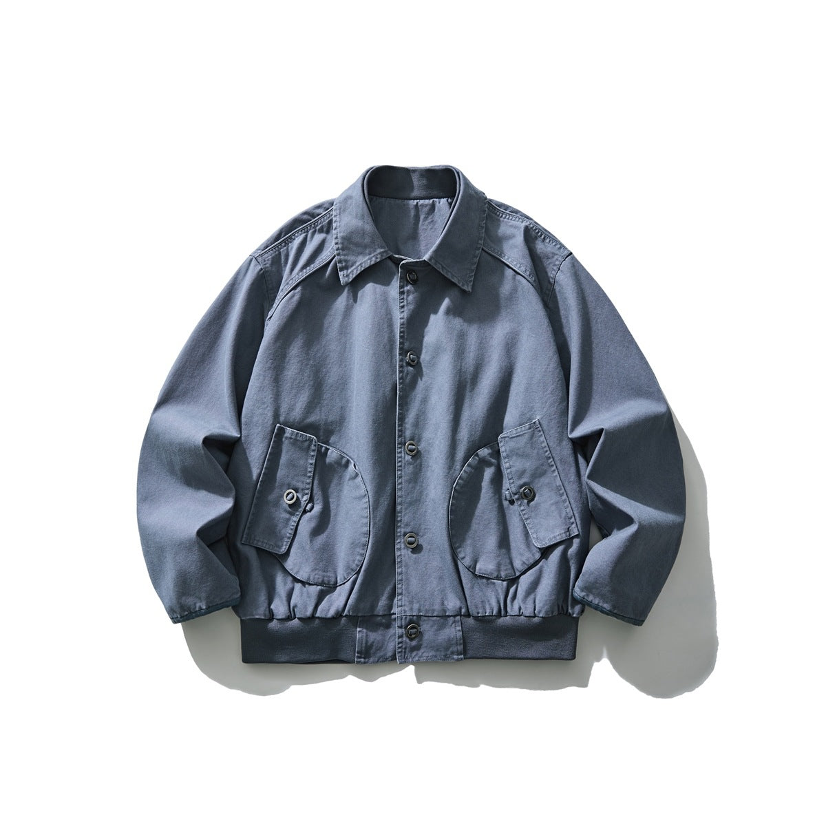 Slate blue collared button-front jacket flat lay with two large flap pockets and ribbed hem