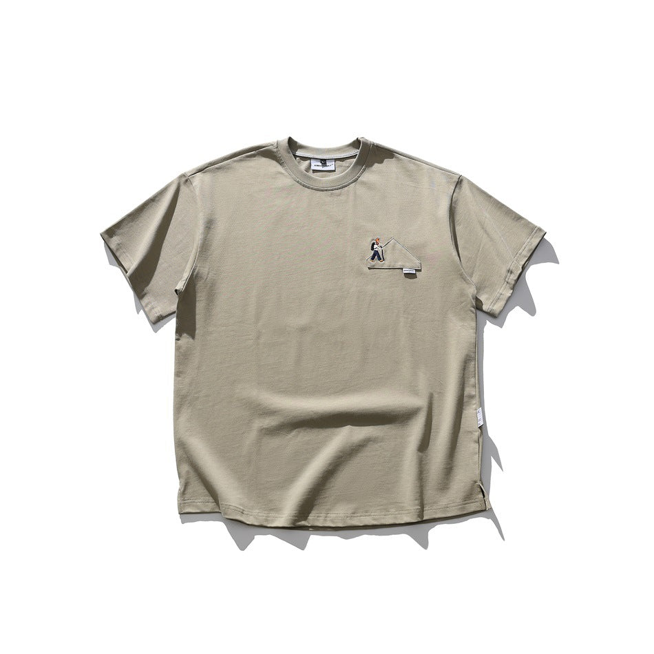 Grayish green short-sleeve crew-neck T-shirt with small embroidered hiker patch on the left chest, flat lay