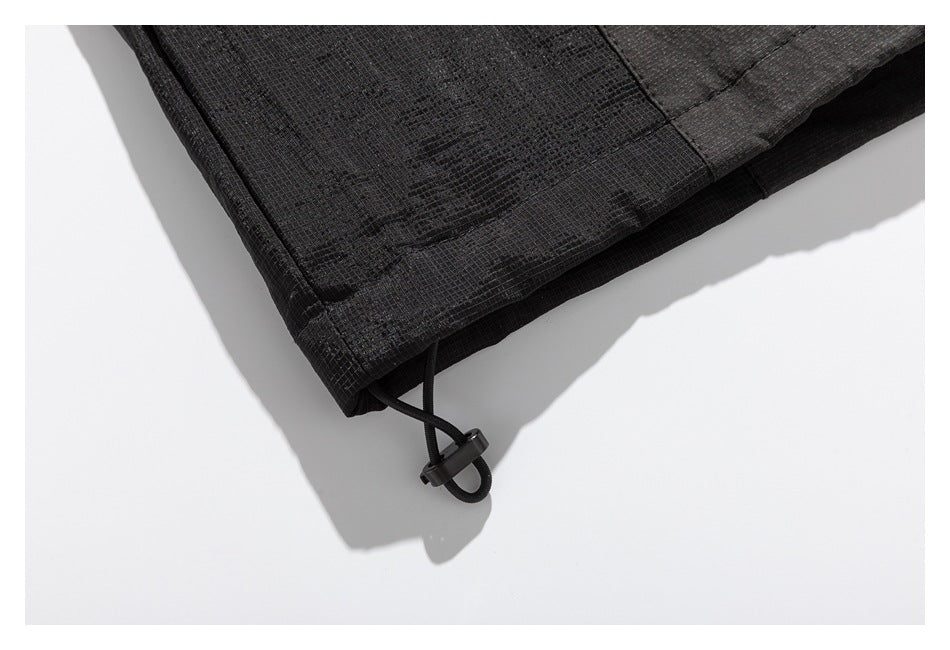 Close-up of a dark garment hem with a black elastic drawcord and cord lock.