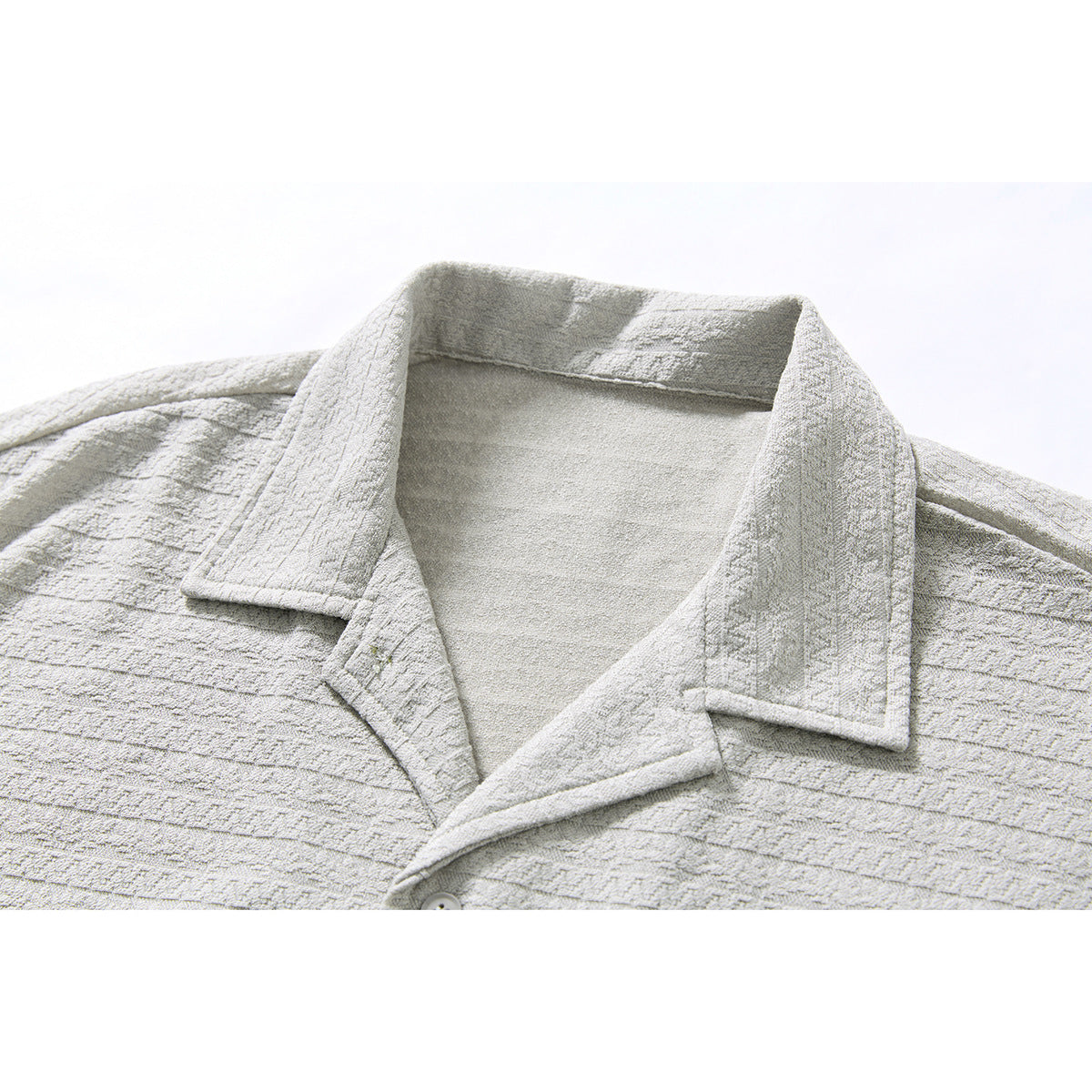 Close-up of a light gray short-sleeve shirt's notched collar and textured horizontal stripe pattern.